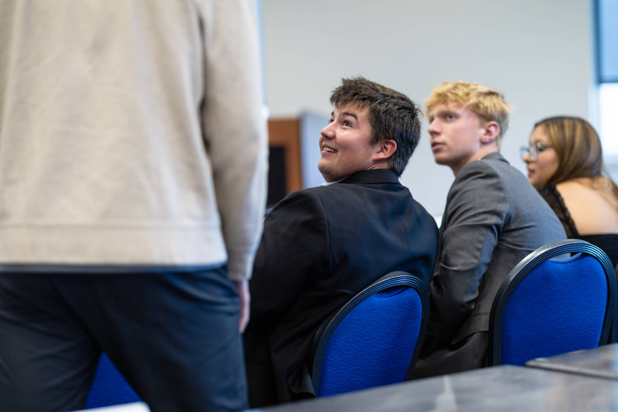 Two student senators sitting and talking with a standing student.